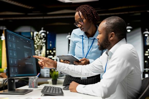 Zwei Mitarbeitende analysieren am Bildschirm digitale Anwendungen für den Einsatz von KI im Arbeitsalltag.
