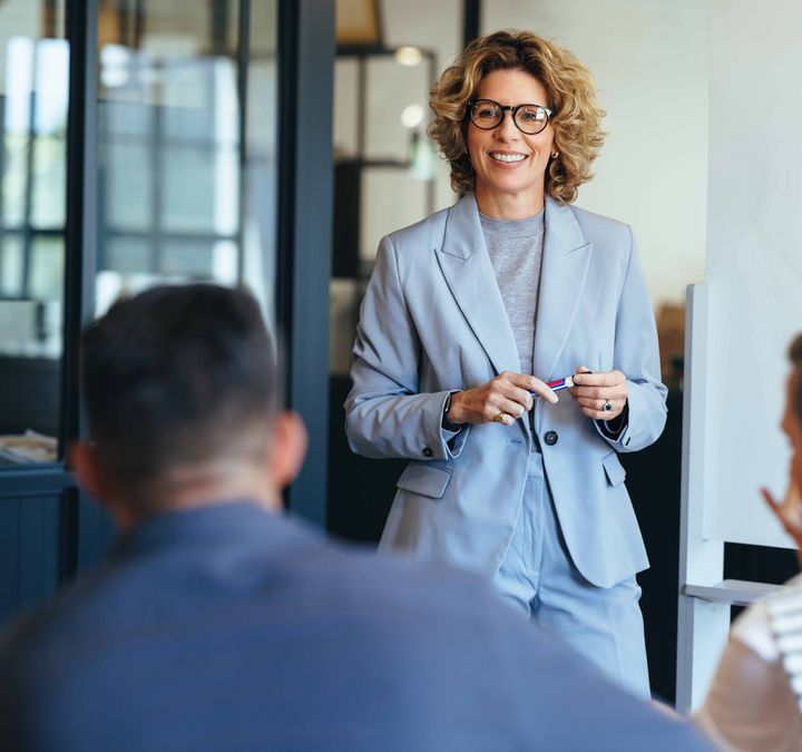 Frau Mitte 40 präsentiert vor ihrem Team im Meeting: Symbolbild für berufliche Neuorientierung mit 40.