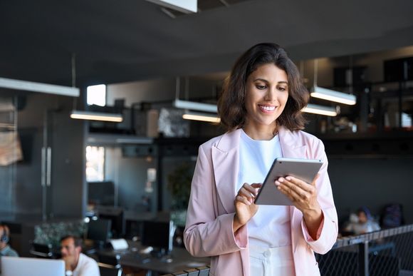 Mitarbeiterin nutzt ein Tablet im Büro und beschäftigt sich mit KI-Tools für den Arbeitsalltag