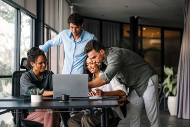 Ein Team schaut auf einen Laptop und nutzt KI am Arbeitsplatz.