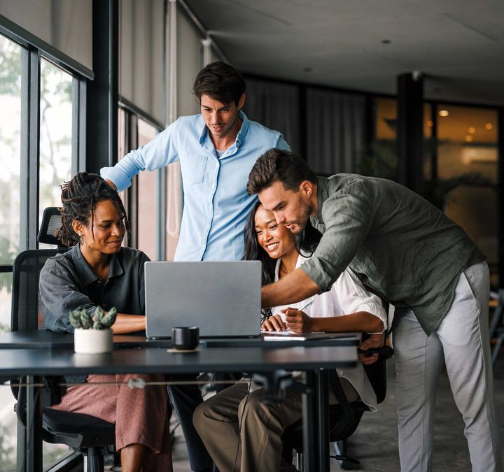 Ein Team schaut auf einen Laptop und nutzt KI am Arbeitsplatz.