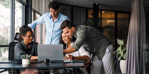 Ein Team schaut auf einen Laptop und nutzt KI am Arbeitsplatz.