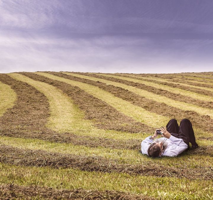 Mann liegt im Feld mit seinem Handy
